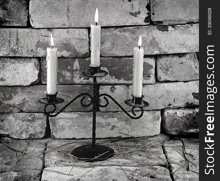 Black and white image of three burning candles on stone wall background. Black and white image of three burning candles on stone wall background