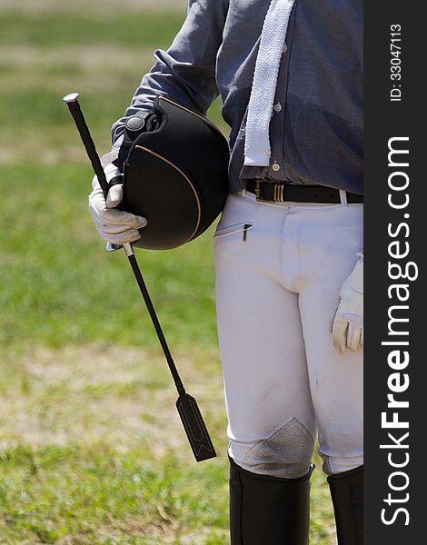 Jockey in uniform with a whip and helment .