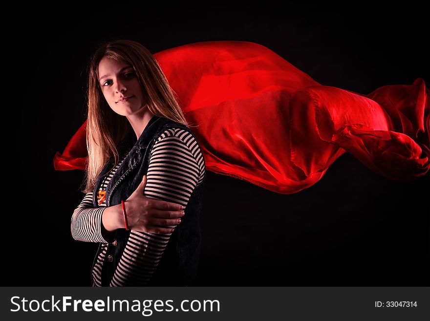 Beautiful girl against red fabric in the dark with long blond hair