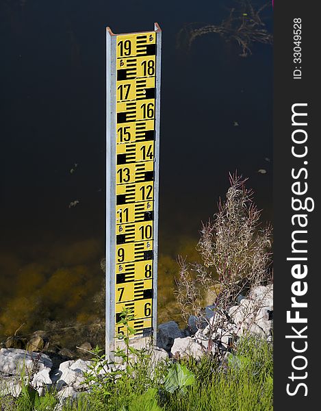 A yellow water level detector on the edge of a lake
