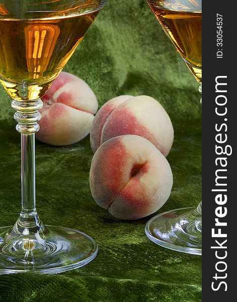 White wine and ripe peaches on green velvet