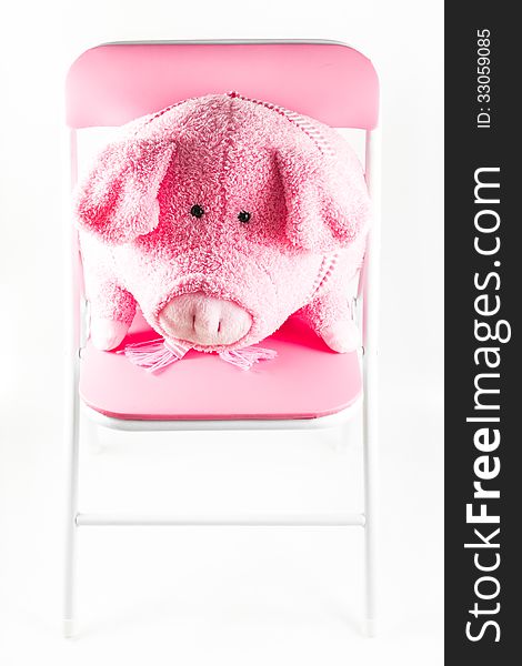 Pink fabric pig is on a chair isolated on white