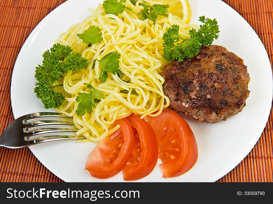 Burger rissole and spaghetti with vegetables at plate. Burger rissole and spaghetti with vegetables at plate