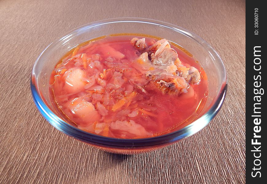 Red soup with chicken on brown background