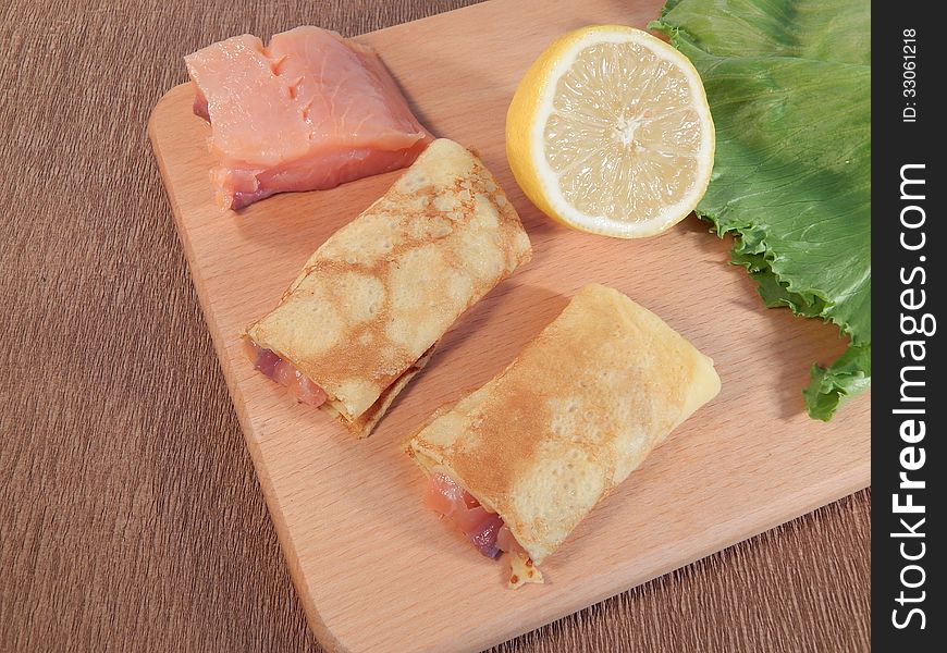 Pancakes with red fish salmon on wooden stand