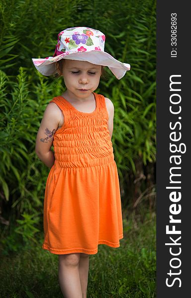 Portrait of a shy girls in colorful hat and orange dress. Portrait of a shy girls in colorful hat and orange dress