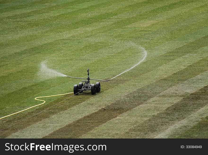 A Sprinkler Watering Newly Laid Grass Turf. A Sprinkler Watering Newly Laid Grass Turf.