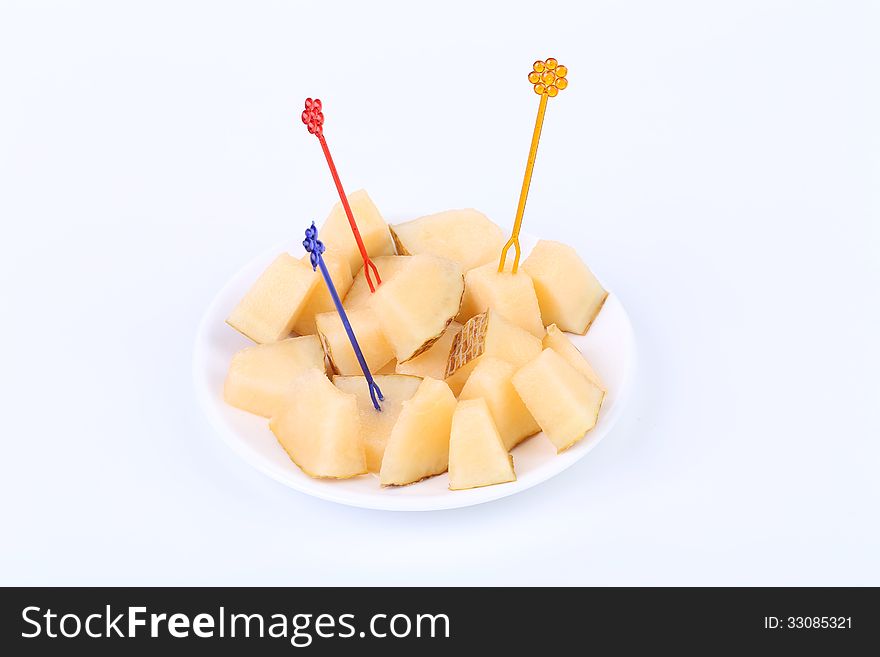 Fresh melon cubes on a plate. White background.