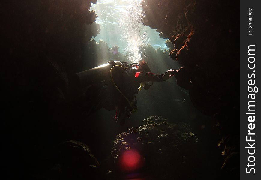 Diver lit by shafts of sunlight while exploring caverns in the southern Red Sea. Diver lit by shafts of sunlight while exploring caverns in the southern Red Sea