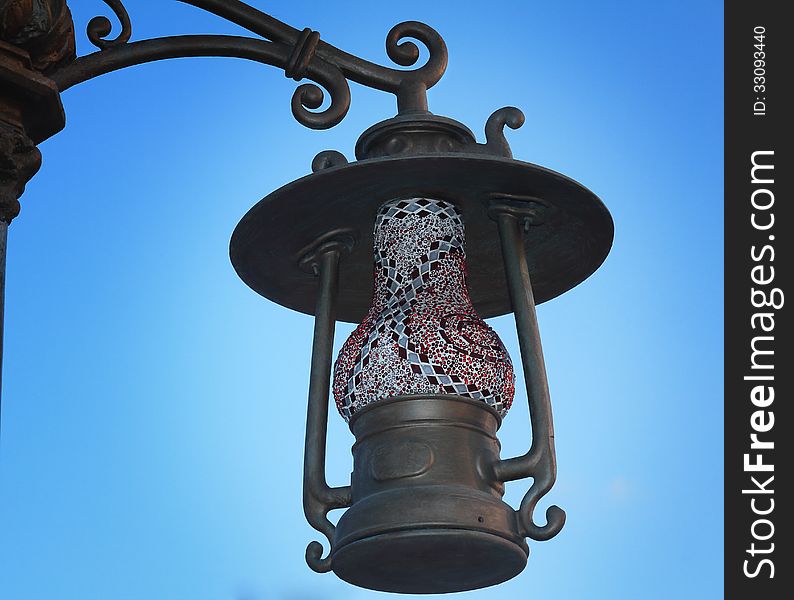 Lamp on a pole on the street, made in the form of antique lamp. Photographed on the background of blue sky. Lamp on a pole on the street, made in the form of antique lamp. Photographed on the background of blue sky.