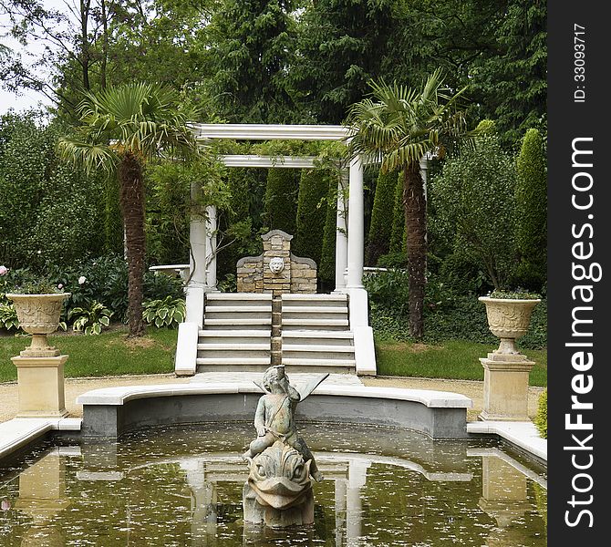 Pont with statues and palm trees in a formal Italian garden