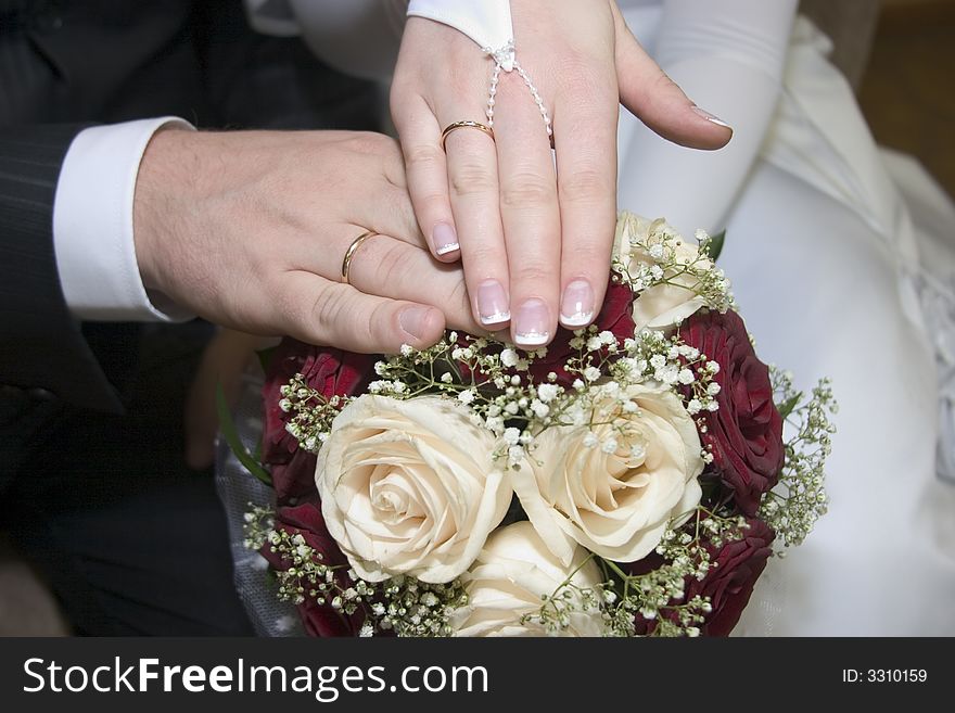 The hands of groom and bride on the flowers. The hands of groom and bride on the flowers