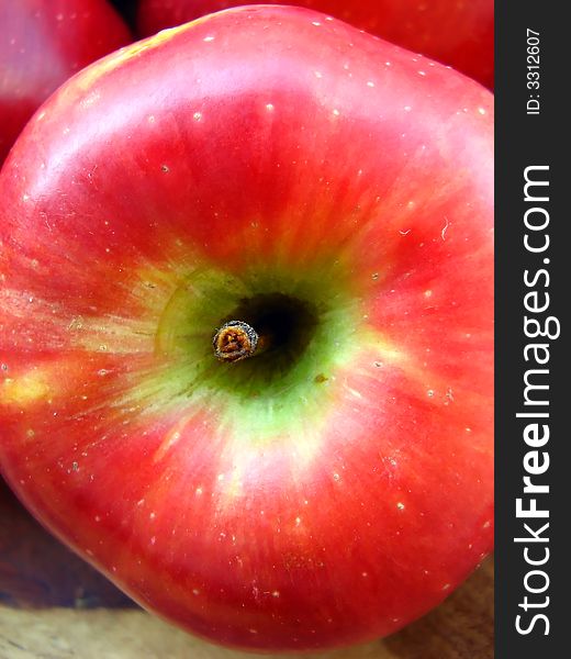 A macro of a red apple inside a bowl with other apples