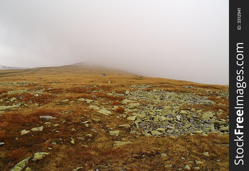 Fog coming down from a mountain peak on a autumn landscape. Fog coming down from a mountain peak on a autumn landscape