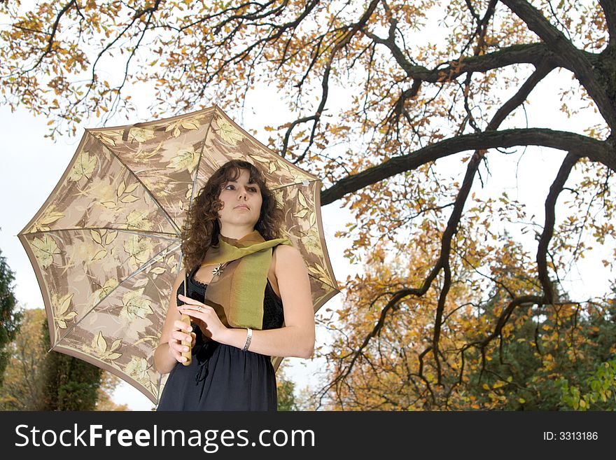 Girl with umbrella standing at autumn park.