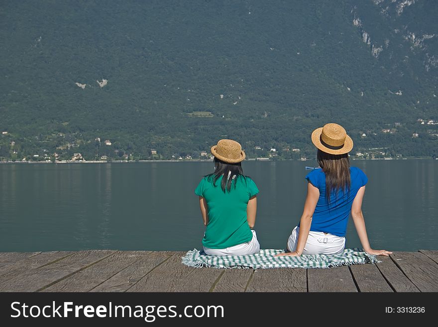 Young woman sitting on a pontoon at the edge of a lake. Young woman sitting on a pontoon at the edge of a lake