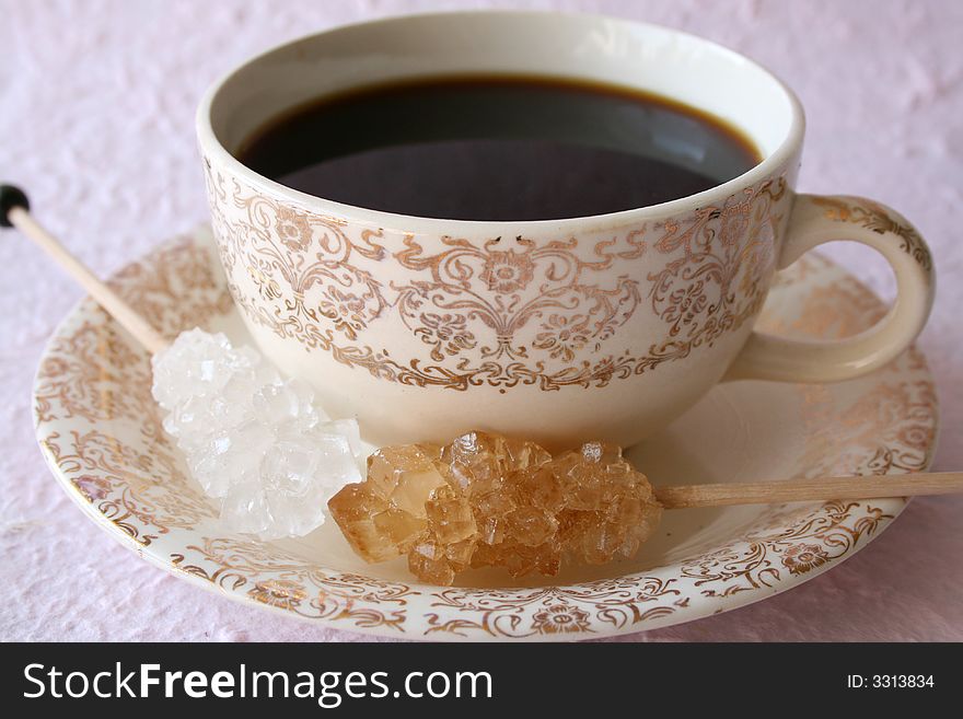 Antique coffee cup with two sugar crystals on a pink background. Antique coffee cup with two sugar crystals on a pink background