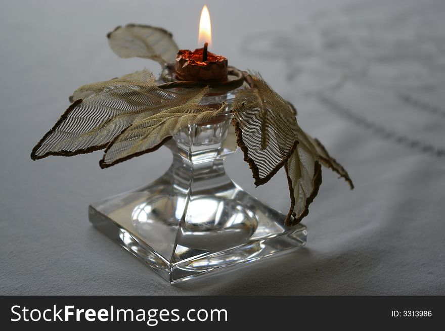 Candle in a crystal candlestick ornated by a golden leaf. Candle in a crystal candlestick ornated by a golden leaf.