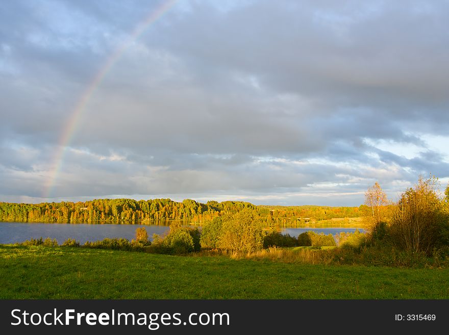 The cloudy sky and autumn rainbow above lake