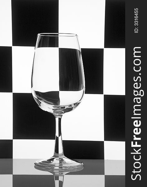 One glass on a checkered black-and-white background. Concept geometry still-life. One glass on a checkered black-and-white background. Concept geometry still-life.