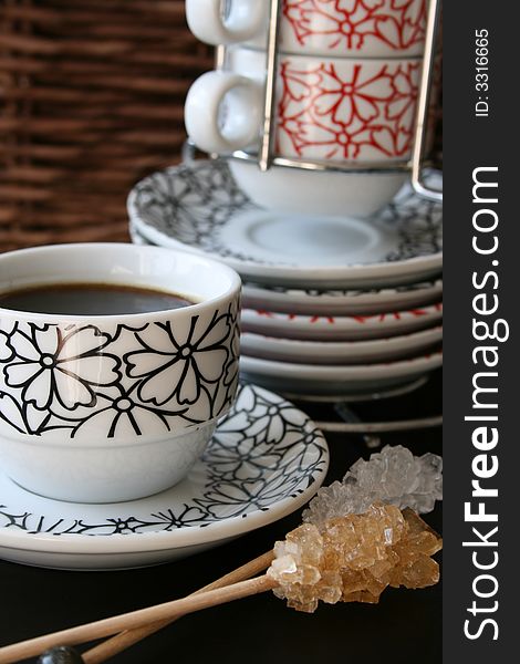Stacked cups in the background with coffee and sugar crystal in the front