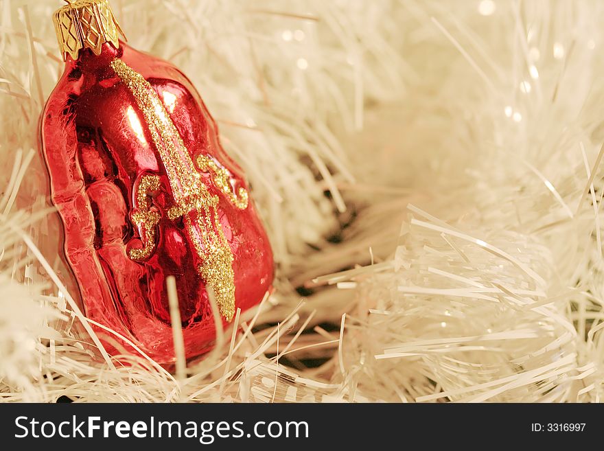 A piece of red and gold Christmas decoration shaped as a violin (cello, contrabass) in a cluster of white glittering strings. A piece of red and gold Christmas decoration shaped as a violin (cello, contrabass) in a cluster of white glittering strings.