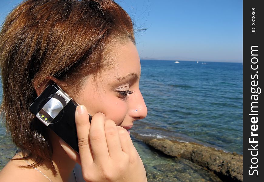 Young woman at the beach is talking to her cellphone. Young woman at the beach is talking to her cellphone