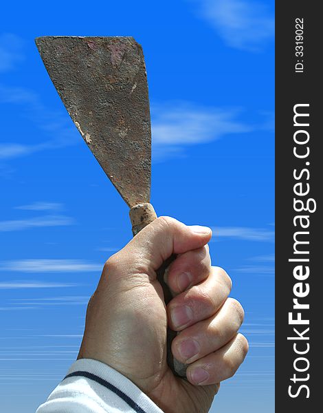 A spatula in hand with the sky of background