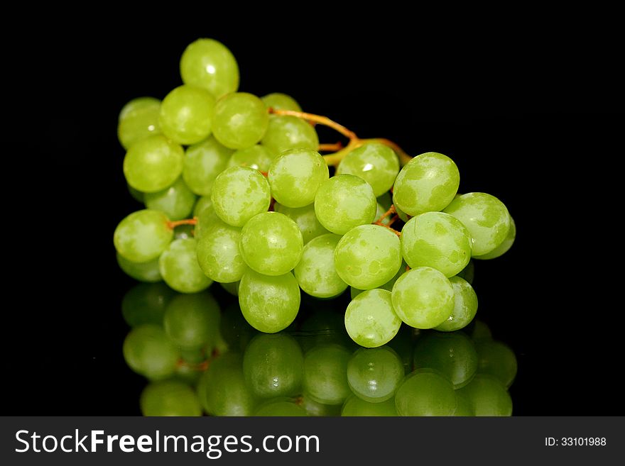 Green Grapes on a reflective plate with black background