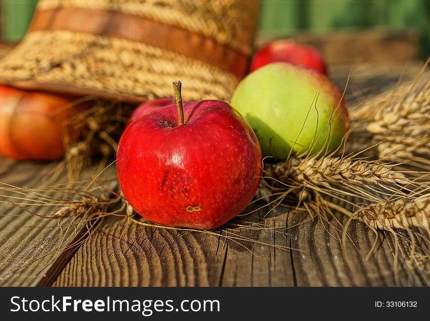 Rural abstract summer still life with apples, ears of wheat and straw hat. Rural abstract summer still life with apples, ears of wheat and straw hat.