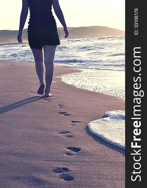 A barefoot girl is walking in the sand