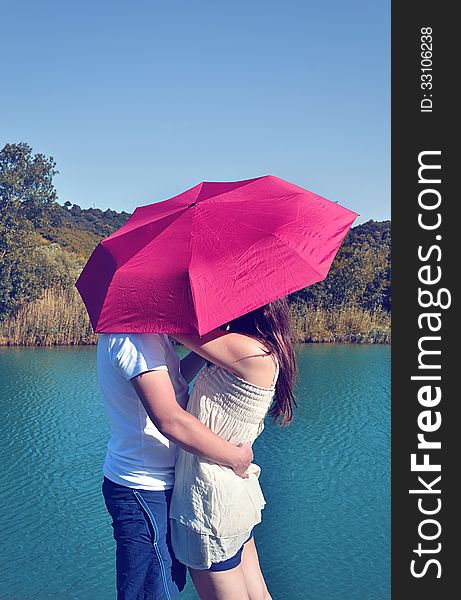 A rocker couple kissing under an umbrella.