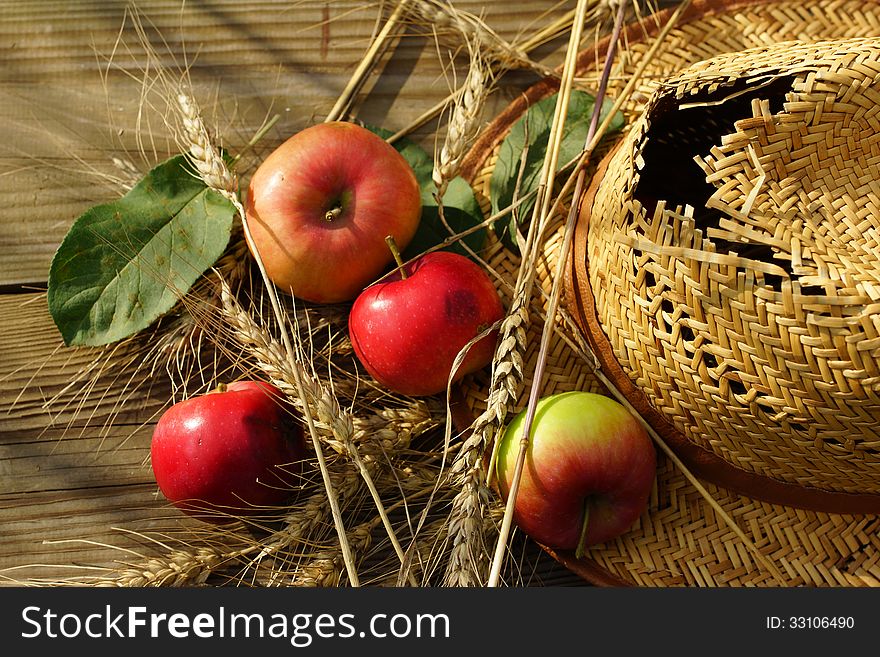 Composition with apples, stalks and straw hat.