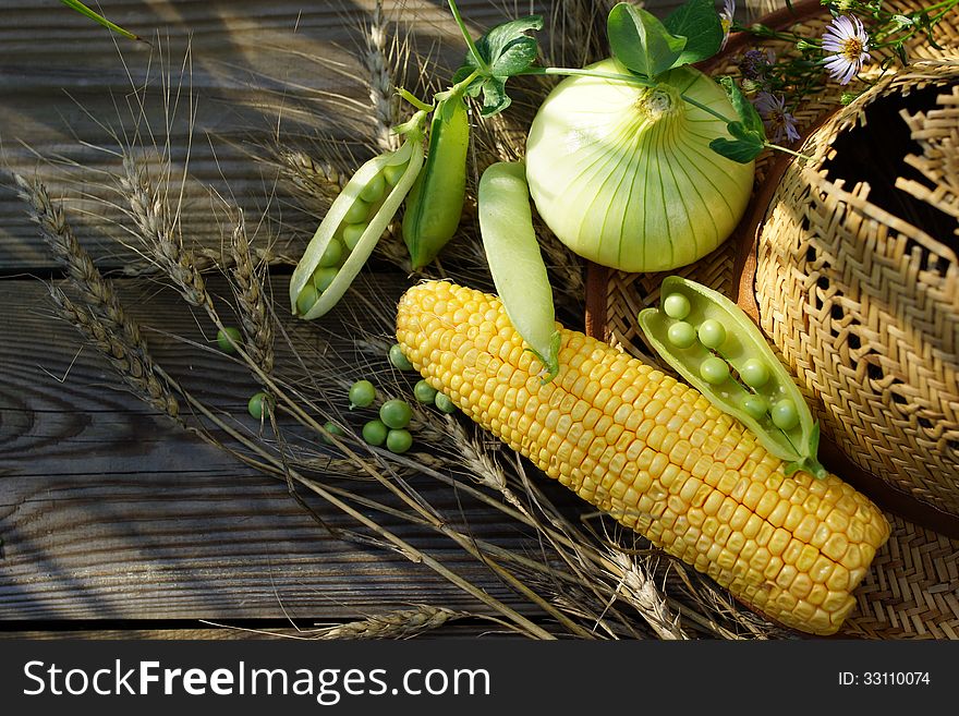 Summer vegetable still life with a green pot, corn, onions and straw hat. Summer vegetable still life with a green pot, corn, onions and straw hat.