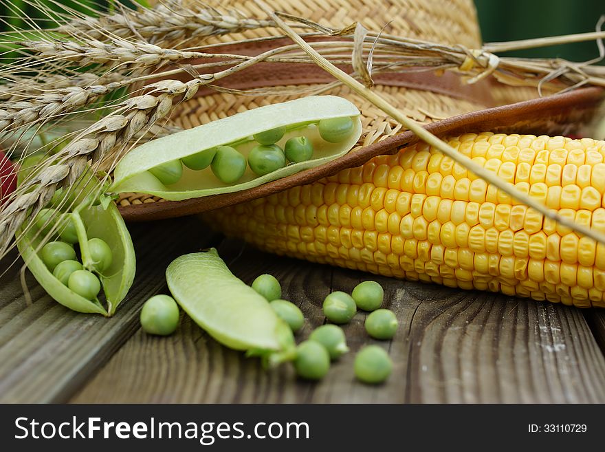 Summer vegetable still life with apples, green pot, corn and straw hat.