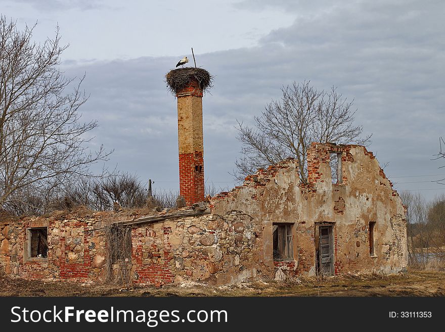 Ruins with a stork's nest on the chimney on cloudy sky background. Ruins with a stork's nest on the chimney on cloudy sky background