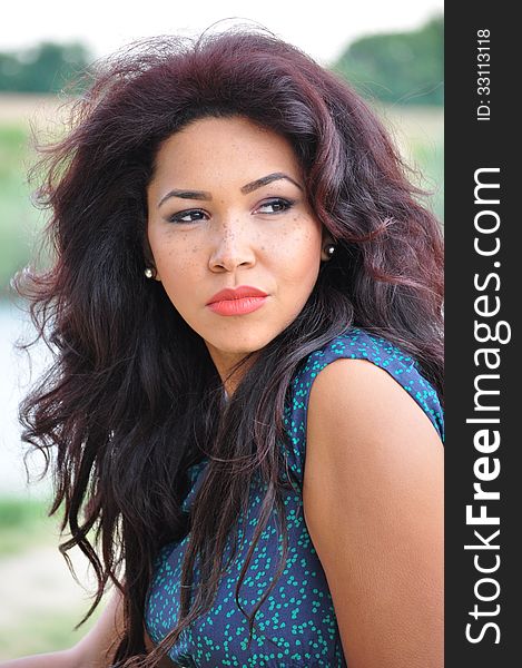 Outdoor portrait of an attractive young woman with long blac hair.