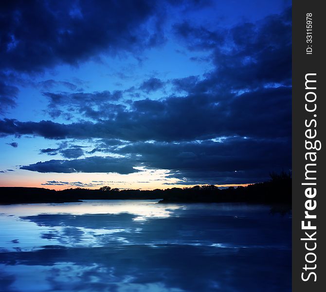 Background of dark sky before a thunder-storm with reflection in the water