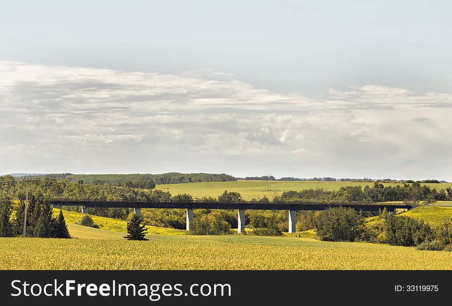 A railway bridge over a gully surrounded by farmland and dotted with trees. A railway bridge over a gully surrounded by farmland and dotted with trees