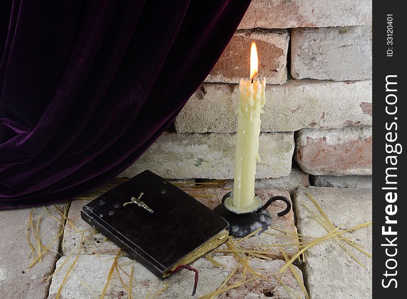 Burning candle with Bible in Gothic castle background