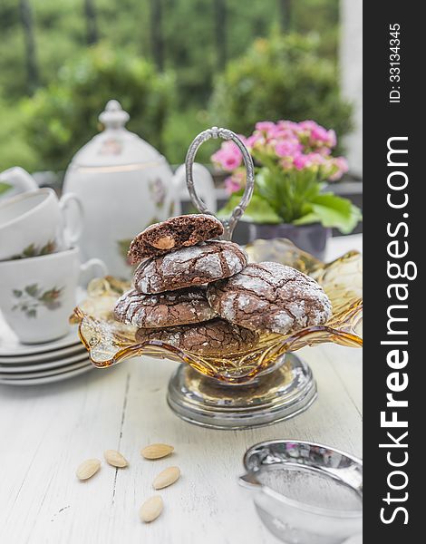 Stacked chocolate and almond cookies with tea set and floers in the backgroudn