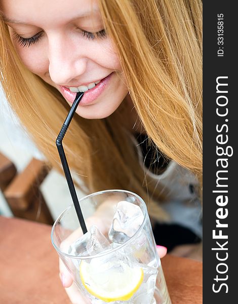 Pretty blonde girl taking a drink on a terrace