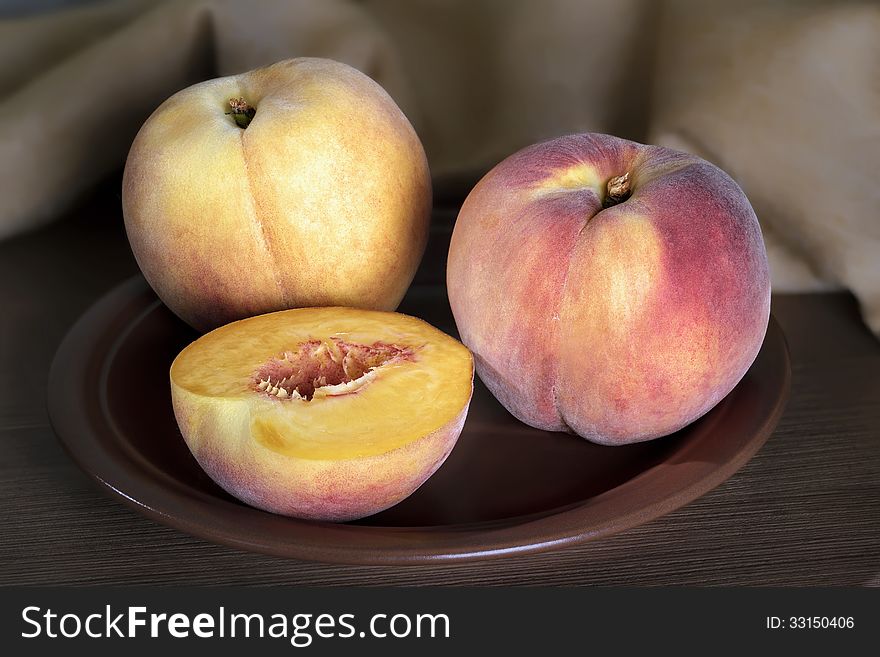 Ripe peaches whole and segments with on a ceramic plate