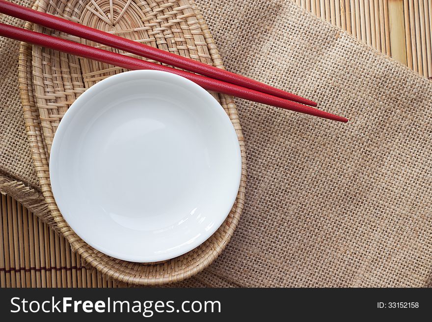 Two chopsticks next to a red and white bowl