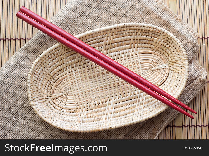 Two chopsticks next to a red and white basket