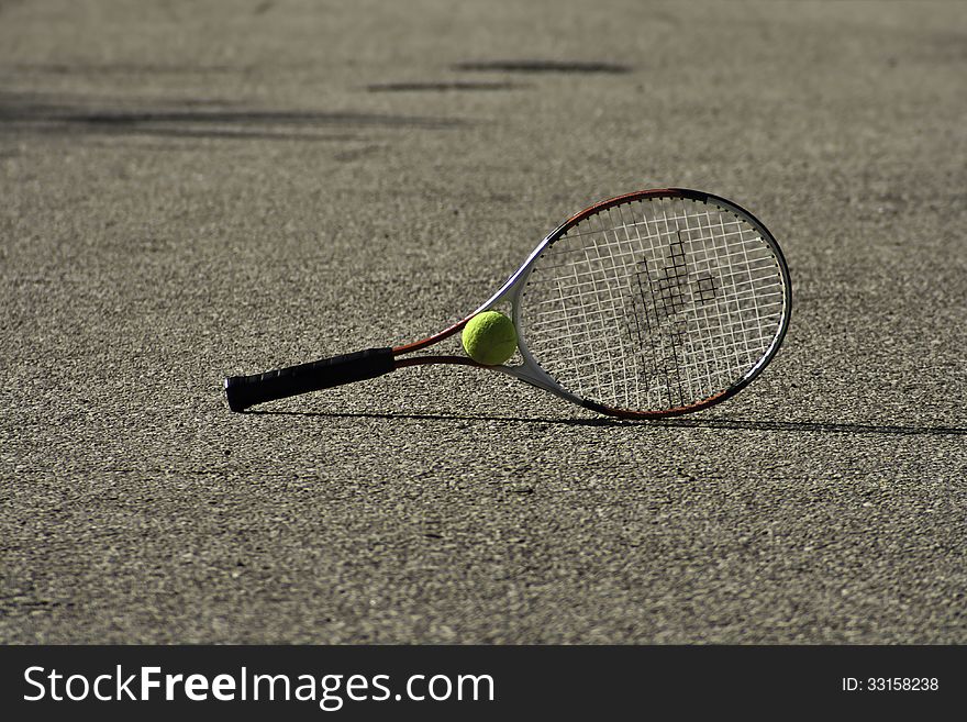 Tennis racket and ball in focus on the ground. Tennis racket and ball in focus on the ground