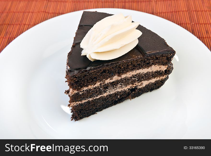 Piece of chocolate cake on white plate at table