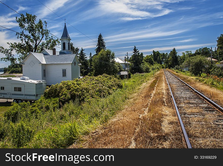 Charlevoix railway with a small white church on a sunny afternoon. Charlevoix railway with a small white church on a sunny afternoon.