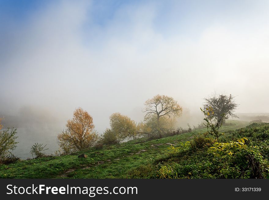 Thick fog on autumn embankment