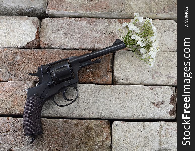 Black retro gun with bunch of flowers on stone background